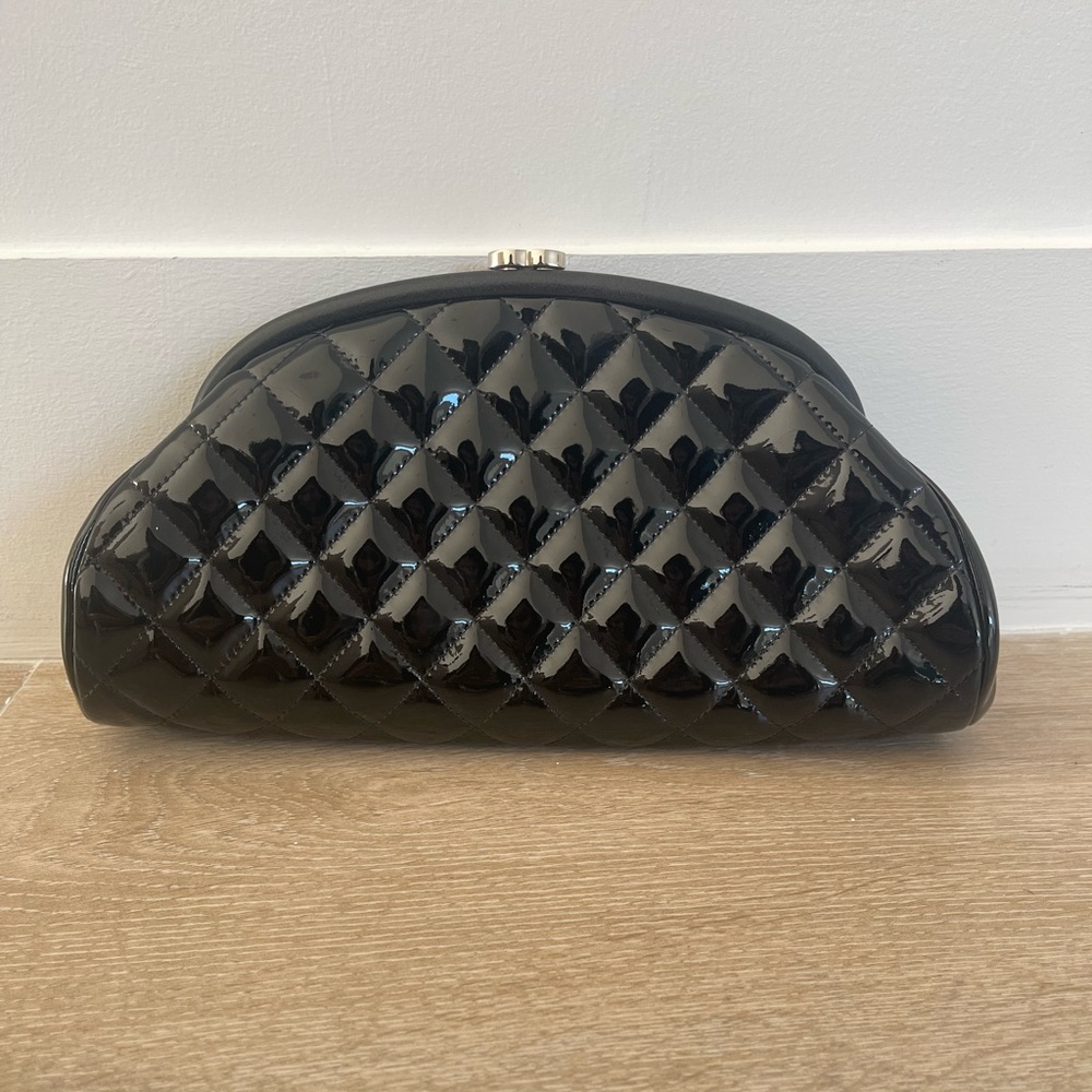 Black patent leather Mademoiselle clutch with silver detail.